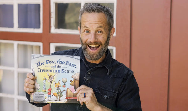 Kirk Cameron holding a book titled 'The Fox, the Fair, and the Invention Scare' in front of a window.