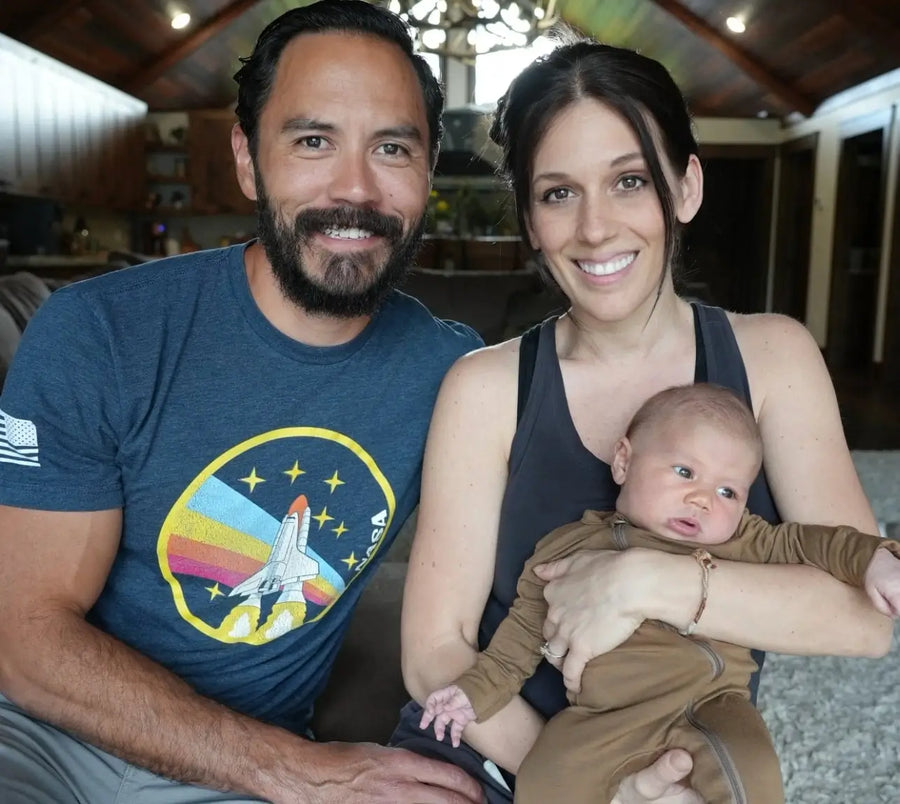Man and woman sitting on a couch with a baby, in a home setting
