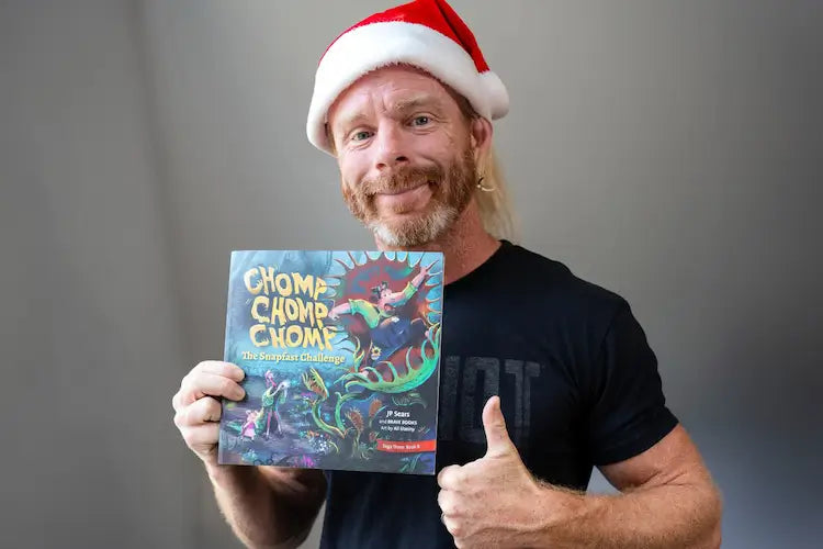 JP Sears smiling with his new children's book, Chomp Chomp Chomp: The Snapfast Challenge
