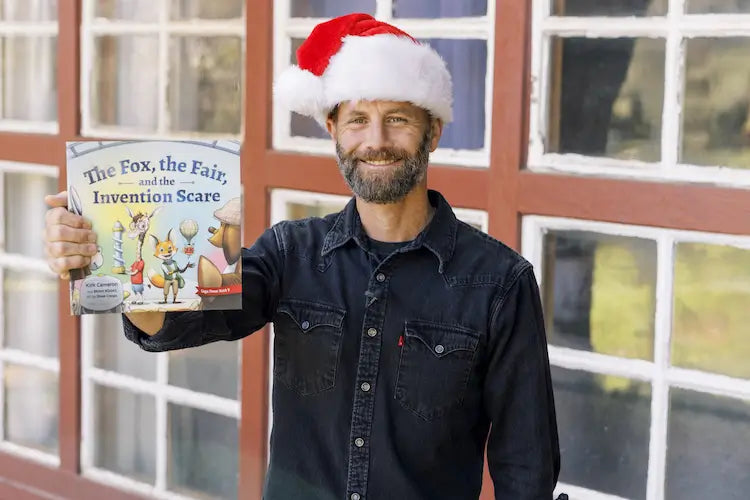 Kirk Cameron smiling with his new children's book, The Fox, the Fair, and the Invention Scare