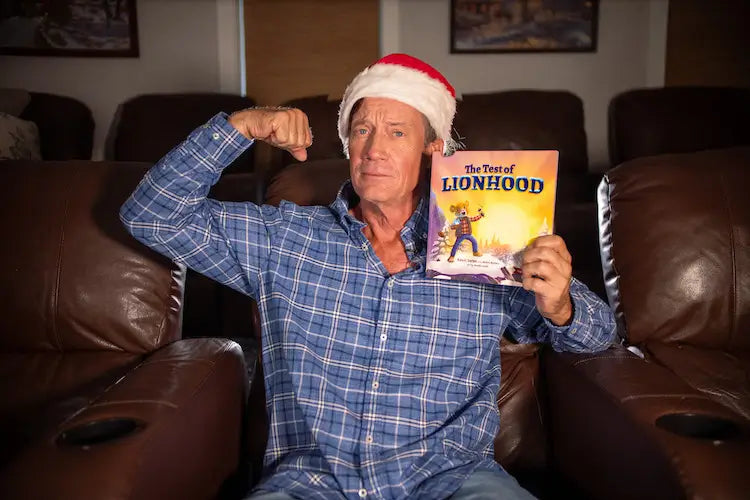 Kevin Sorbo flexing his arm with his new children's book, The Test of Lionhood