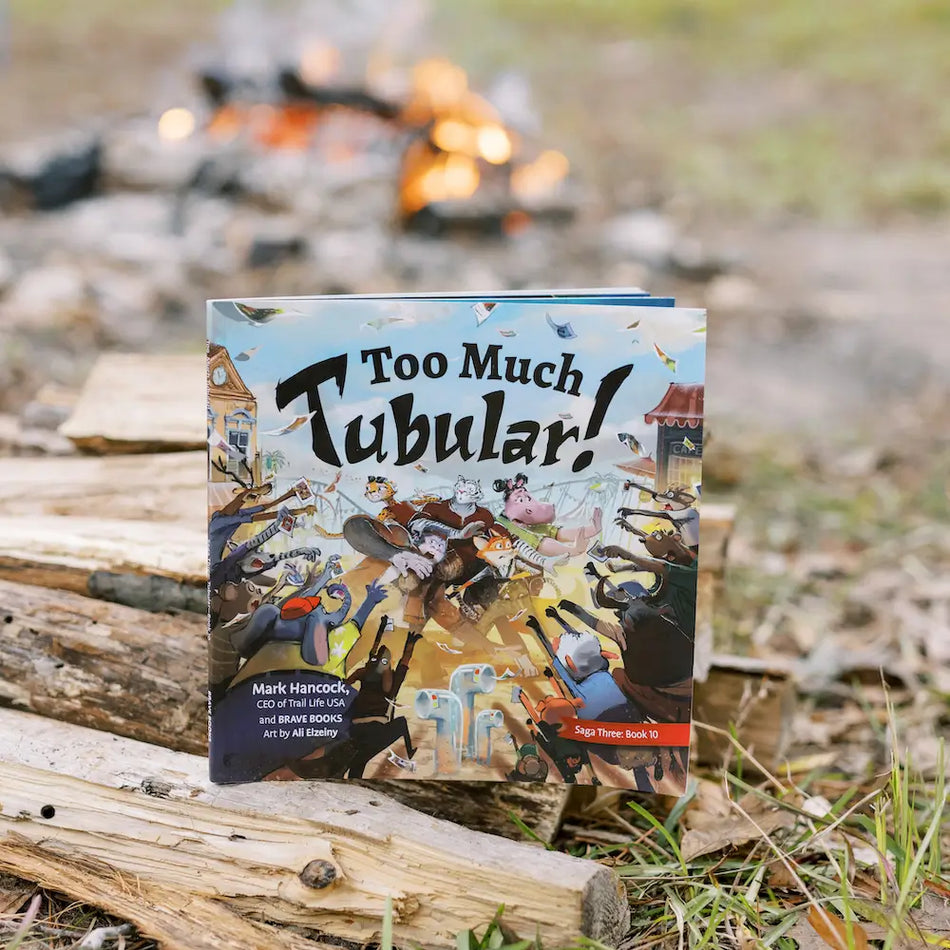 BRAVE Books new children's book, Too Much Tubular, sitting next to a campfire