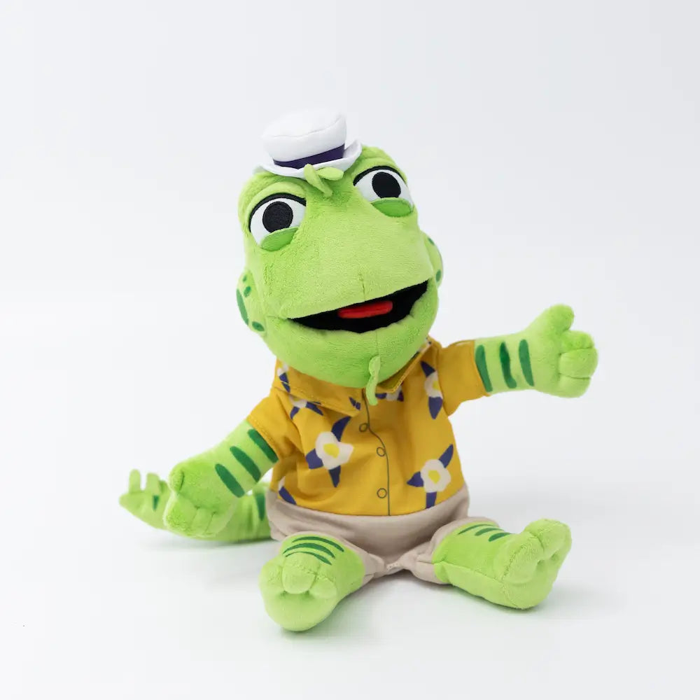 Plush toy iguana puppet wearing a yellow shirt with a pattern on a white background