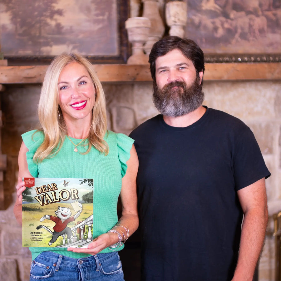 Jep and Jess Robertson standing together, one holding a book titled 'Dear Valor'.