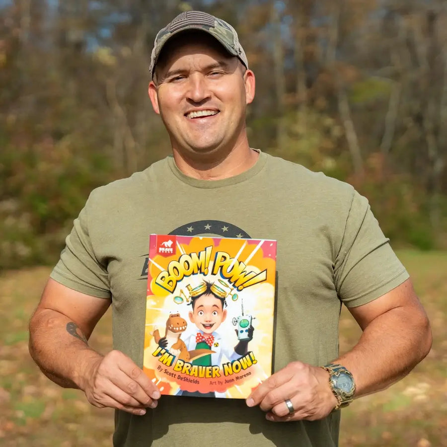 Man holding a book titled 'Boom! Pow! I'm Beaver Now!' outdoors.