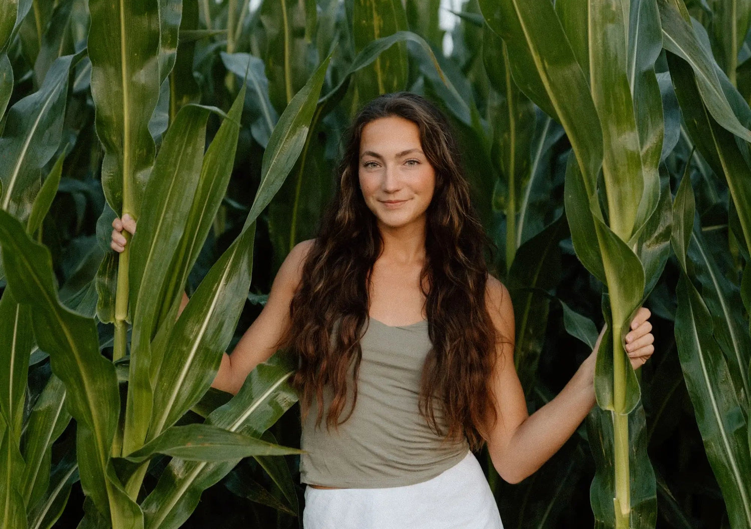 Laura Farms standing among tall corn plants in a field
