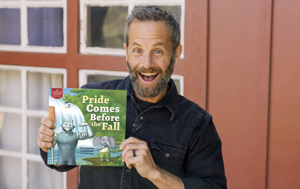 Kirk Cameron smiling and holding his children's book, Pride Comes Before the Fall