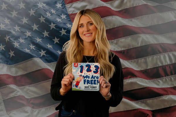 Riley Gaines holding a book in front of a n American flag